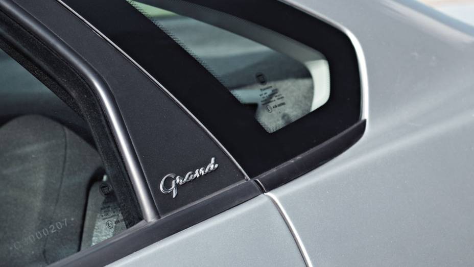 Inscrição "Grand" na coluna da porta | <a href="https://gutenberg.quatrorodas.abril.com.br/carros/testes/fiat-grand-siena-683966.shtml" rel="migration">Leia mais</a>