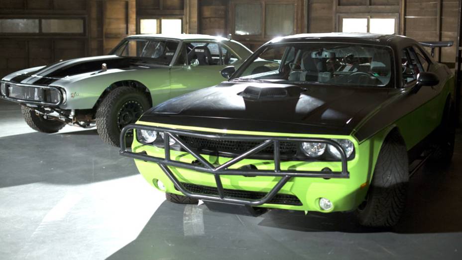 Além do Cuda, Letty também pilota um Dodge Challenger verde bastante modificado; ao fundo, o Chevrolet Camaro de Roman Pearce (Tyrese Gibson) | <a href="https://gutenberg.quatrorodas.abril.com.br/galerias/especiais/gatas-velozes-furiosos-852096.shtml" target="_blank" rel="migration">7</a>