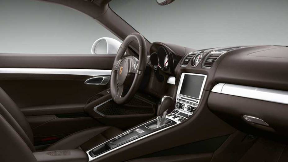 O interior tem revestimento em couro marrom com apliques brancos pela cabine | <a href="https://gutenberg.quatrorodas.abril.com.br/noticias/fabricantes/porsche-cayman-s-ganha-personalizacao-fabrica-894381.shtml" rel="migration">Leia mais</a>