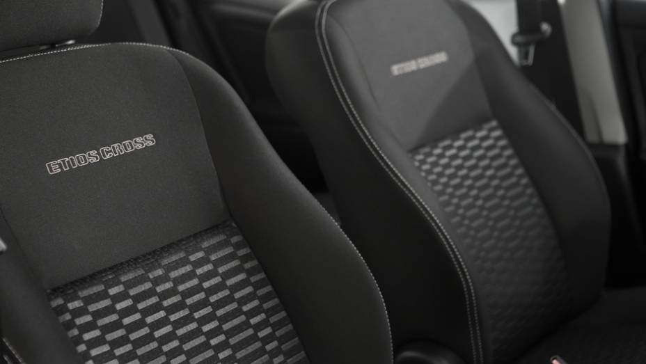 O revestimento Sport Comfort nos bancos ganhou costura branca e apresenta o nome do veículo gravado em alto relevo no encosto dos assentos dianteiros | <a href="https://gutenberg.quatrorodas.abril.com.br/carros/lancamentos/toyota-etios-cross-759424.shtml" rel="migration"></a>