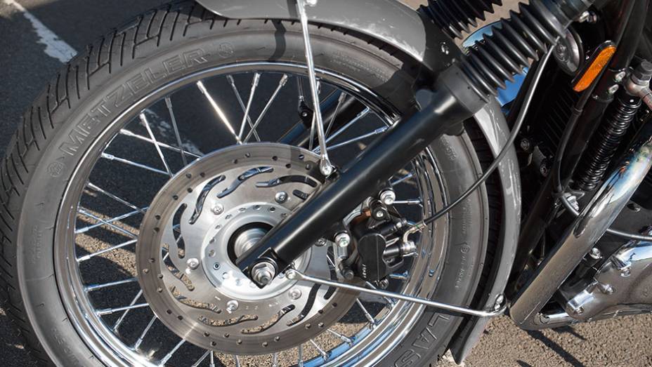 Bons pneus, um disco frontal e rodas raiadas na versão T100 | <a href="https://gutenberg.quatrorodas.abril.com.br/moto/testes/triumph-bonneville-t100-741213.shtml" rel="migration">Leia mais</a>