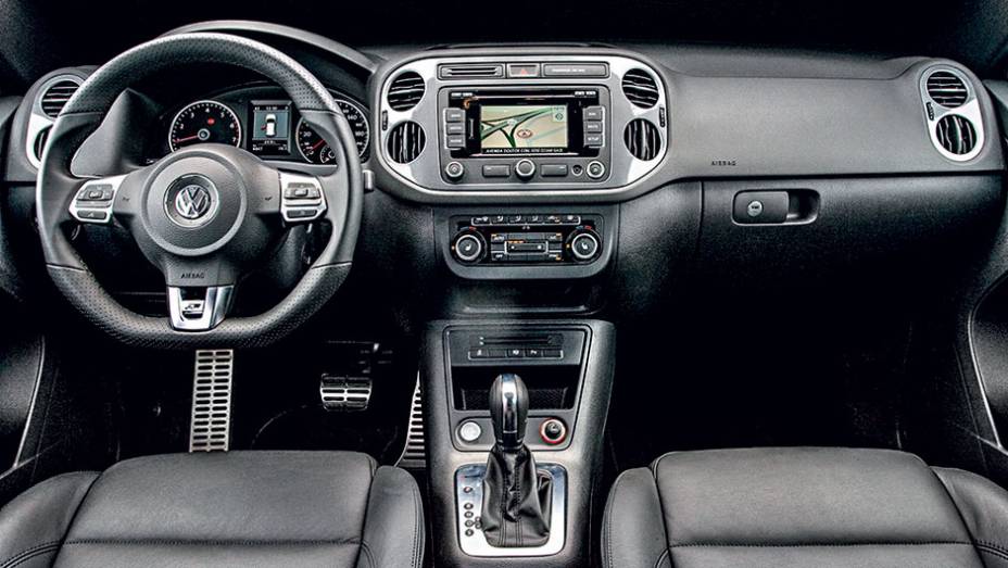 Interior possui volante de três raios com base achatada | <a href="https://gutenberg.quatrorodas.abril.com.br/carros/lancamentos/vw-tiguan-r-line-726908.shtml" rel="migration">Leia mais</a>