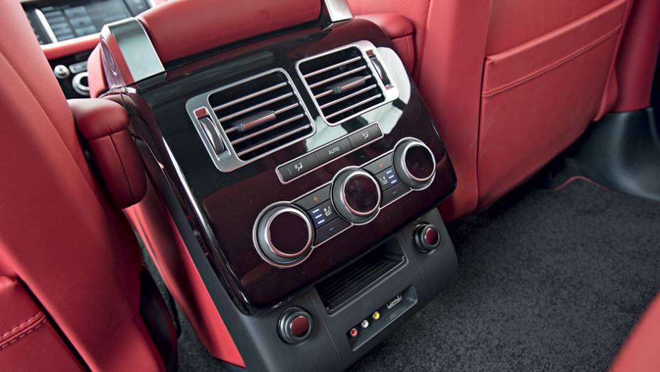 Atrás, um console abriga controles de ventilação e entrada auxiliar | <a href="https://gutenberg.quatrorodas.abril.com.br/carros/testes/land-rover-range-rover-vogue-738240.shtml" rel="migration">Leia mais</a>