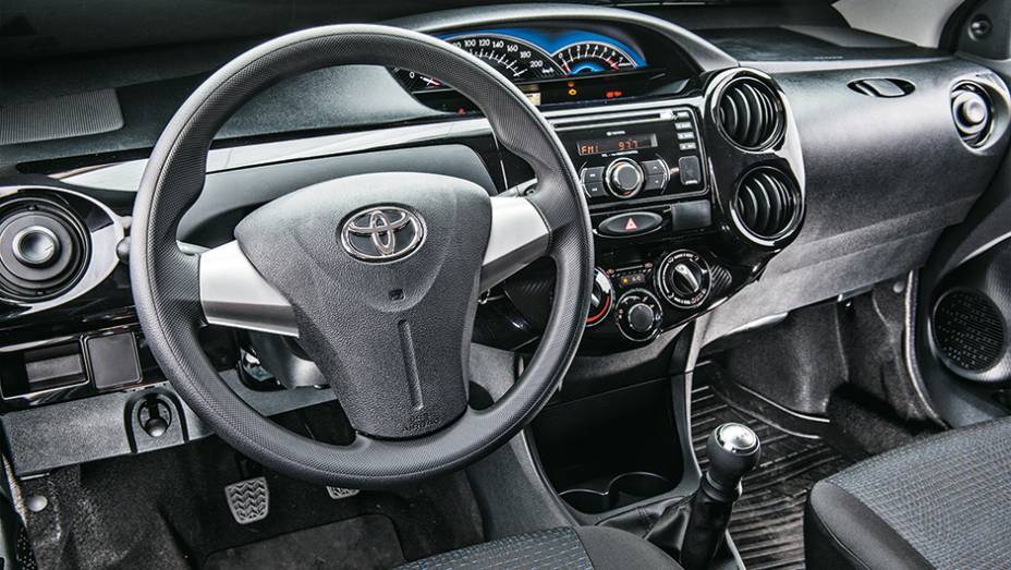 Painel tem tons escuros e um aplique em piano black | <a href="https://gutenberg.quatrorodas.abril.com.br/carros/comparativos/hatches-compactos-779934.shtml" rel="migration">Leia mais</a>