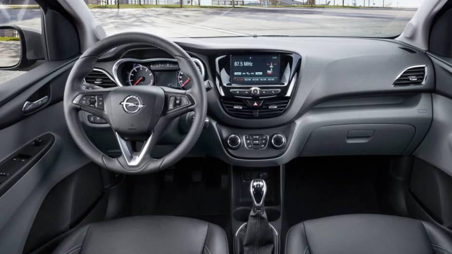 Console central com tela do sistema de entretenimento lembra a do Peugeot 208 | <a href="https://gutenberg.quatrorodas.abril.com.br/noticias/saloes/genebra-2015/opel-lanca-karl-europa-819122.shtml" rel="migration">Leia mais</a>